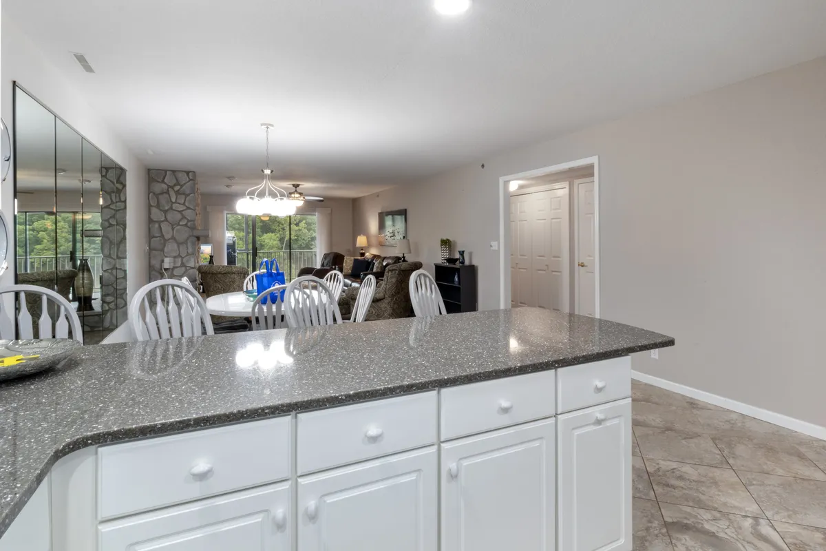 An open-concept kitchen area with a kitchen island, adjacent stone wall, and a view into the dining and living spaces. The setup promotes a seamless flow for entertaining and keeping the chef connected to guests or family.