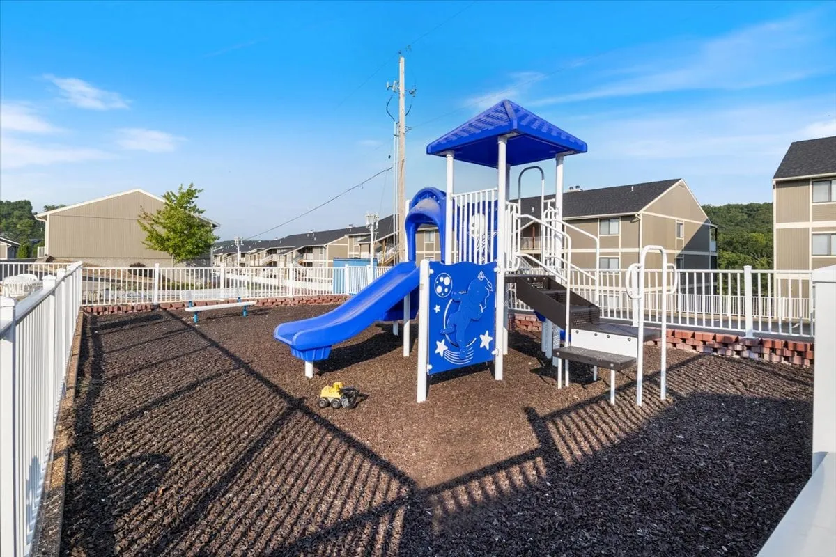 A joyful playground scene with slides and fenced play equipment, inviting children to explore and play. The area is bright and energetic, ideal for family gatherings and outdoor games after a day on the lake.