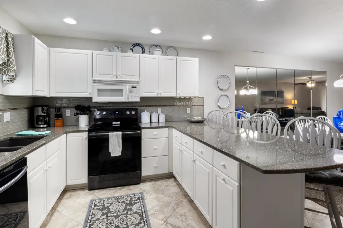 A cozy kitchen setting with black appliances, a granite countertop, white cabinetry, and decorative plates. The space feels ready for cooking, entertaining, and celebrating special occasions with loved ones.