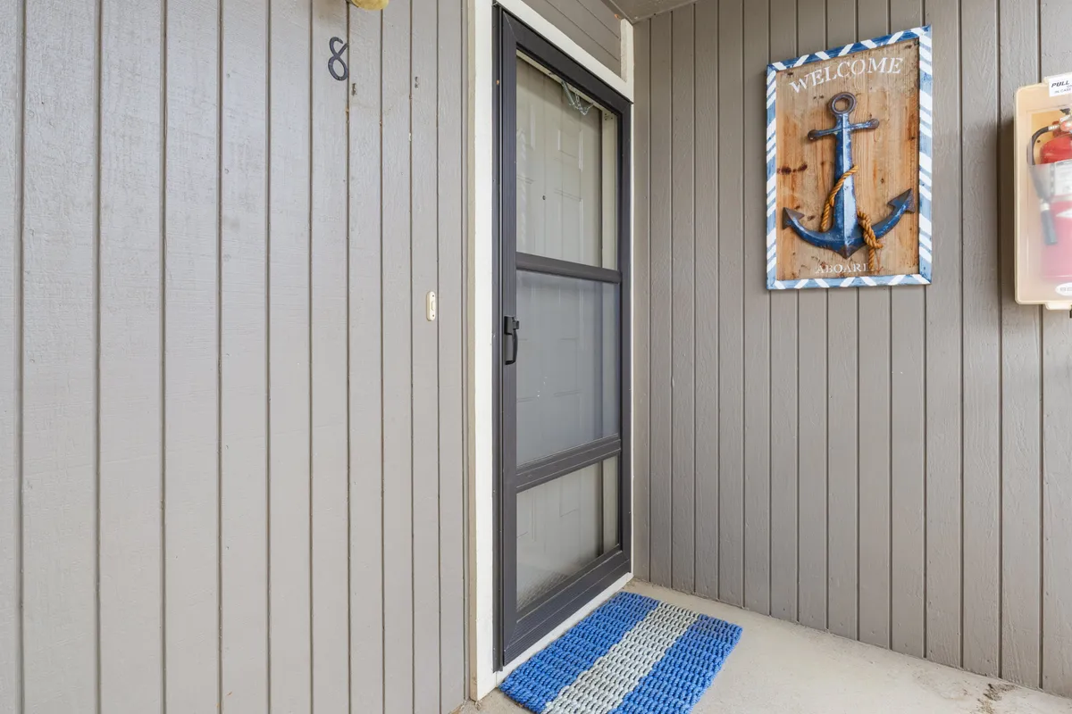 This image captures the entryway with a 'welcome' sign, anchor decor, and a doormat, setting a friendly and inviting first impression for guests as they enter the condo.