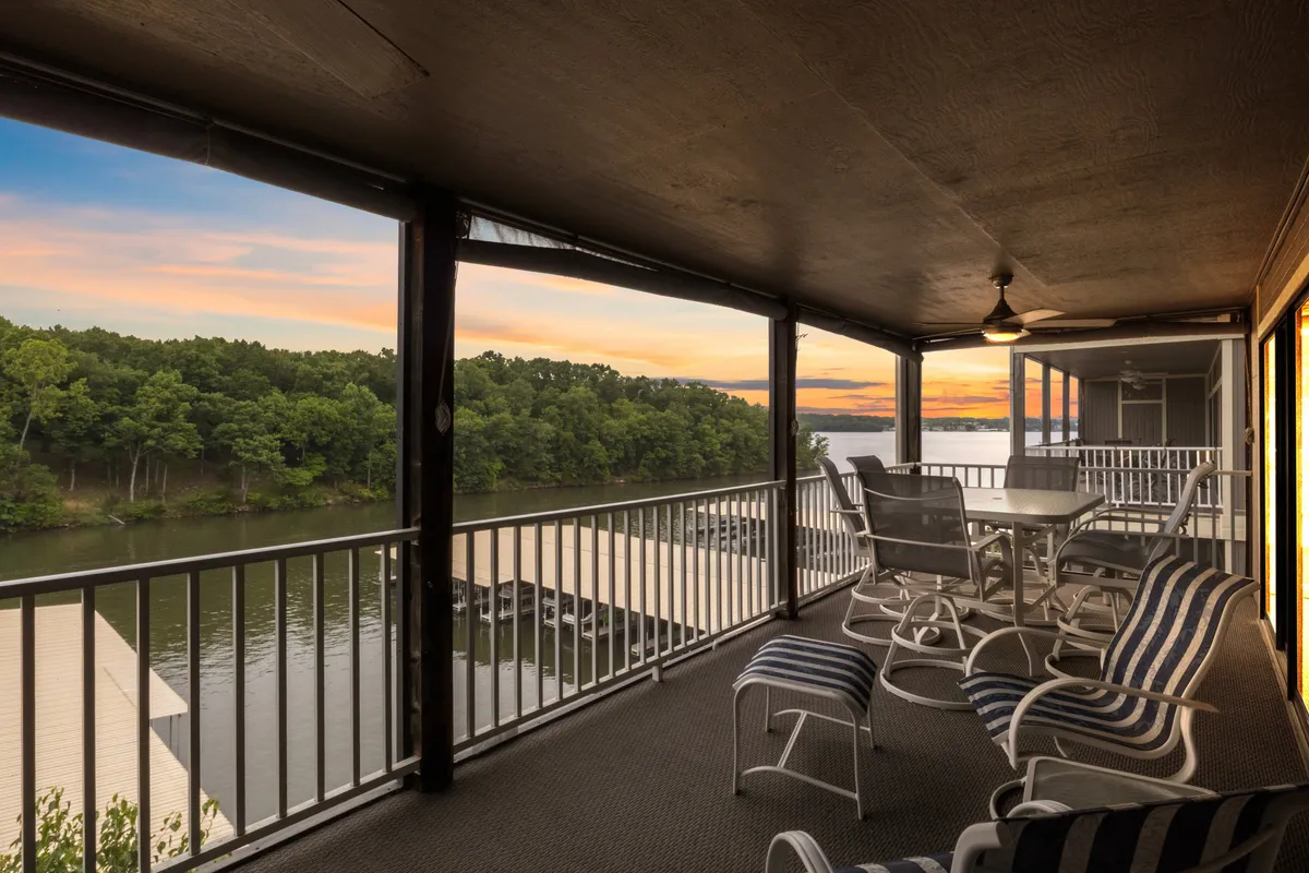 The image shows a serene outdoor space at the condo, with a cozy dining table and comfortable seating arranged to overlook the sparkling waters of Lake of the Ozarks. The setting is perfect for enjoying peaceful sunsets, morning coffee with lake views, or stargazing on clear nights, offering a tranquil atmosphere ideal for relaxing or entertaining guests.