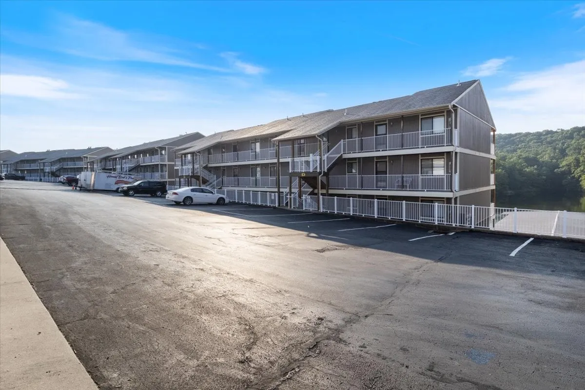 An exterior shot featuring multiple residential buildings set amidst landscaped greenery, with open walkways and a parking area. The communal space is friendly and welcoming, perfect for quick strolls or casual encounters with neighbors—an environment where pets are easily accommodated.